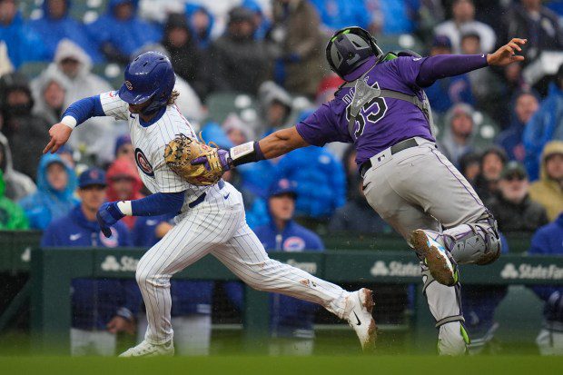Chicago Cubs second baseman Nico Hoerner, left, gets caught between third and home and is tagged out by Colorado Rockies catcher Elias Diaz during the seventh inning of a baseball game, Monday, April 1, 2024, in Chicago. (AP Photo/Erin Hooley)